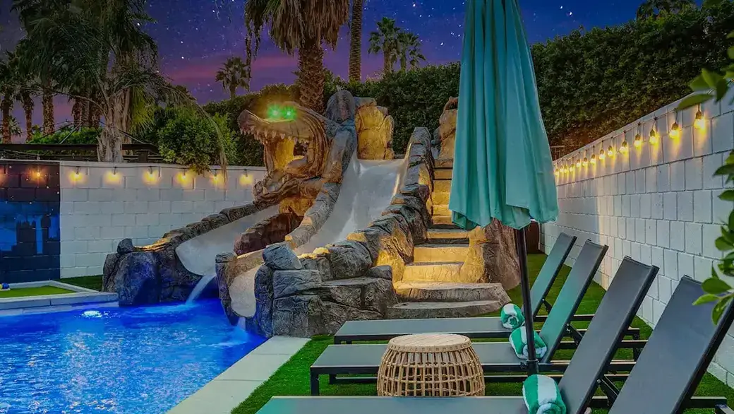 the backyard of a vacation rental home called Forever Young located in Indio, California. The home is Peter Pan-themed and features a large pool with a crocodile-themed waterslide