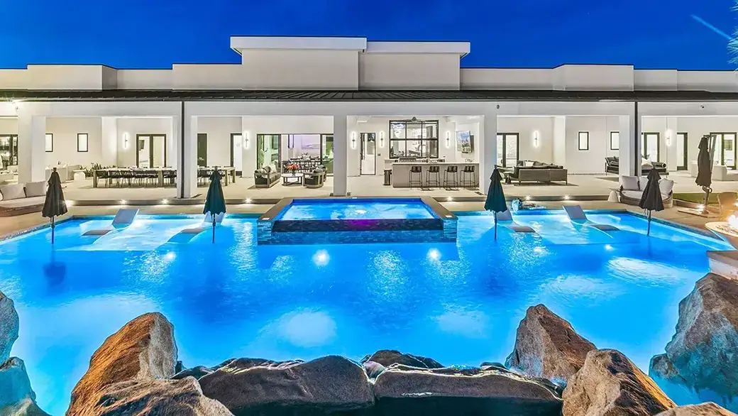 a luxury vacation rental with a swimming pool illuminated at night