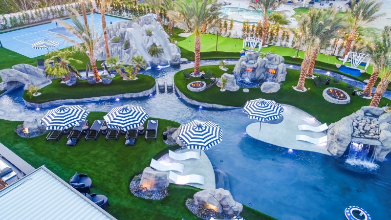 Luxury Airbnb pool with hot tub surrounded by palm trees at sunset