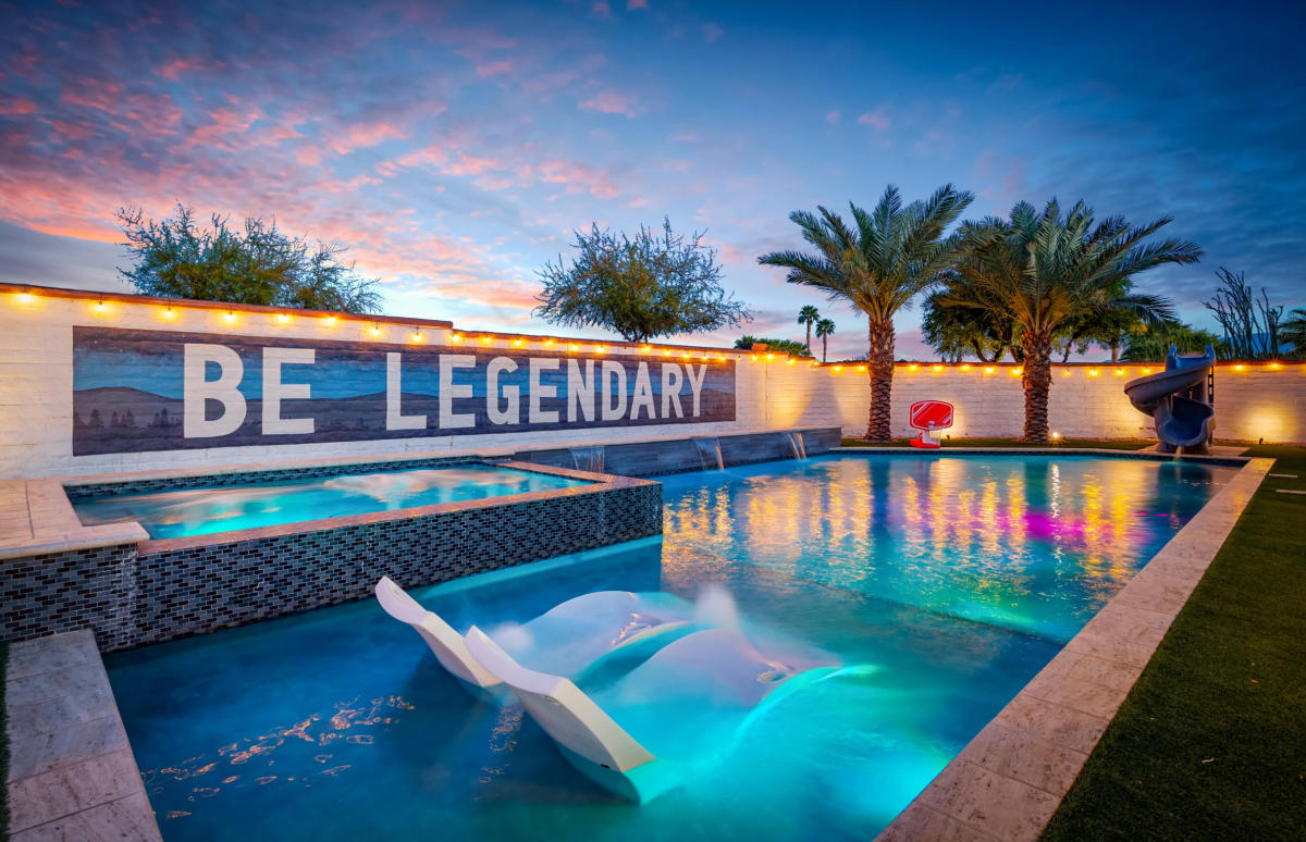 Large pool with built in lounge chairs and attached hot tub at a luxury vacation rental property.