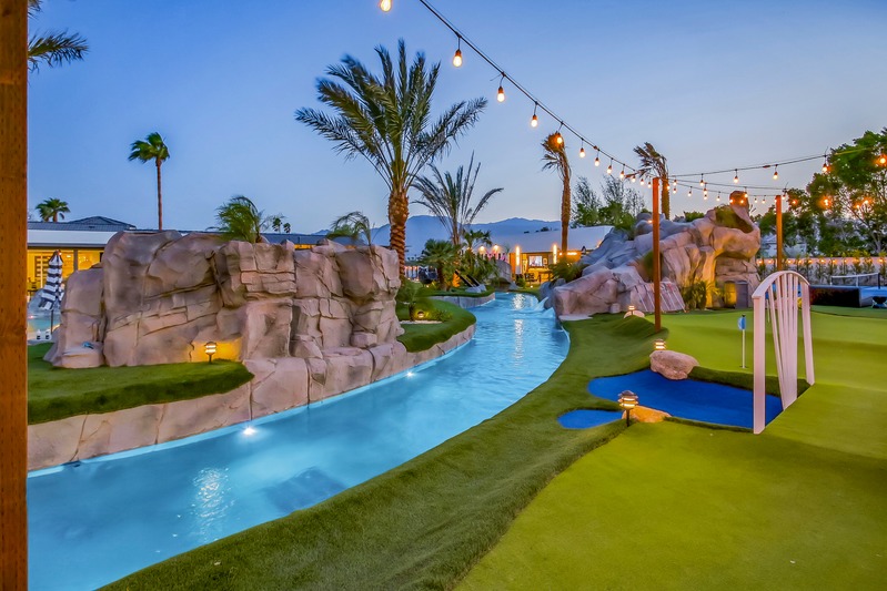 Lazy river pool with palm trees and string lights at dusk